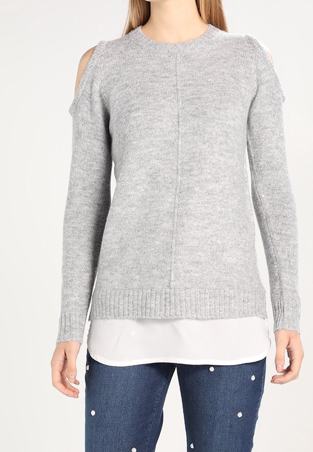 Grijze gebreide trui met uitsneden bij de schouders, geribbelde manchetten en zoom. Draag het over een witte gelaagde blouse en combineer het met blauwe spijkerbroek.