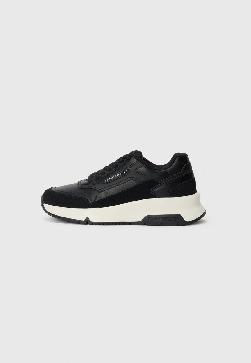 Czarne sneakersy z połączeniem skóry i zamszu. Masywna biała podeszwa środkowa i czarna podeszwa zewnętrzna, z wyraźnym przeszyciem i detalem logo.