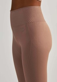 Legginsy z wysokim stanem w kolorze przykurzonego różu, wykonane z teksturowanej tkaniny z ukośnymi prążkami i małym logo serca z boku.