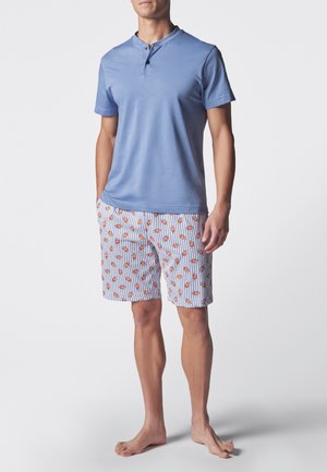 Camicia azzurro chiaro a maniche corte con colletto e due bottoni; abbinata a pantaloni corti con motivo di pesci arancioni su strisce bianche e blu.