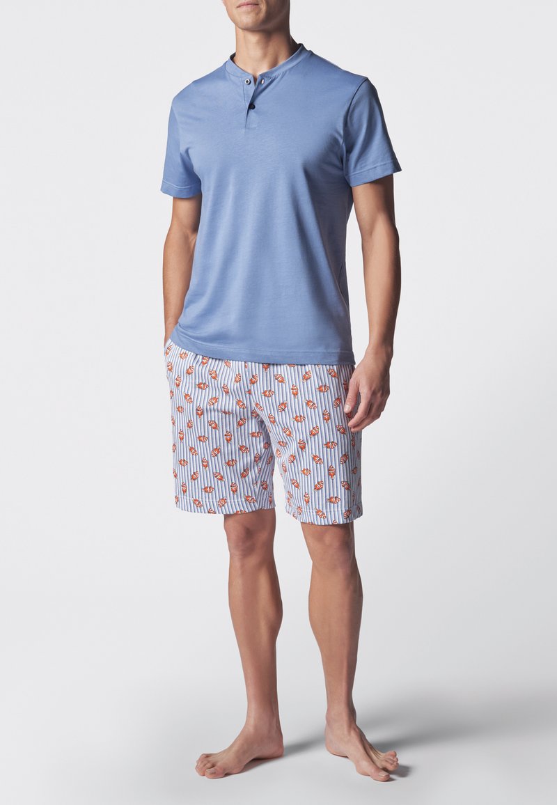 Camicia azzurro chiaro a maniche corte con colletto e due bottoni; abbinata a pantaloni corti con motivo di pesci arancioni su strisce bianche e blu.