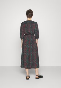 Robe noire avec un motif floral coloré, mi-longue, taille élastique, manches 3/4, et assortie de sandales noires. Tissu lisse, coupe décontractée.