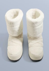 Hvide støvler i kunstpels med slaskede design, runde toppe, tekstureret overflade og gummisåler, med elastiske stropper hen over fronten.