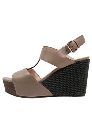 Beżowe skórzane sandały na koturnie z wycięciami i regulowanym paskiem na kostkę. Posiadają teksturowaną czarną plecioną platformę oraz drewniany detal na obcasie.