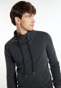 Schwarzer, strukturierten Pullover mit hohem Kragen, ausgestattet mit einem Kordelzug und metallischen Enden, eng anliegenden Ärmel und einem subtilen Punktemuster.