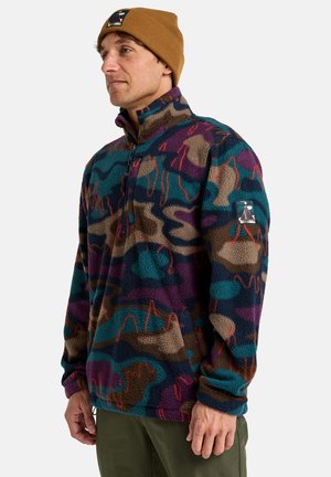 Sudadera de forro polar con un patrón de camuflaje multicolor, que incluye púrpura, azul verdoso y beige. Cuenta con media cremallera y un logo bordado en la manga.