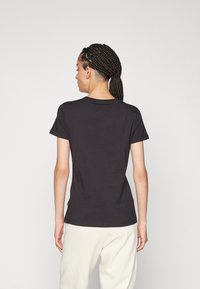 Camiseta negra de manga corta, cuello redondo, ajuste Slim, hecha de suave tela de algodón, con un diseño liso y sin gráficos ni adornos visibles.
