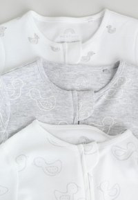 Three baby bodysuits: one white with grey duck patterns, one grey with white duck outlines, and one plain white with similar patterns.