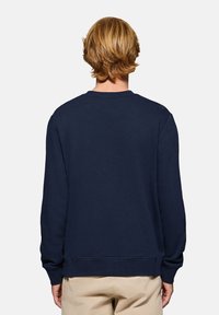 Mörkblå sweatshirt, bomullsmaterial, rundad hals, ribbade muddar och nederkant, avslappnad passform, slät textur, inga synliga mönster eller logotyper.