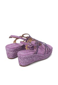 Sandalias de cuña moradas con suela de yute trenzado, múltiples correas entrelazadas y cierre de hebilla. Textura suave y diseño de plantilla acolchada.
