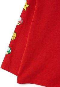 Rotes Baumwoll-T-Shirt mit bunten Grafikdrucken von Pilzen, Münzen und Sternen entlang des Ärmels, mit einer glatten, weichen Textur.