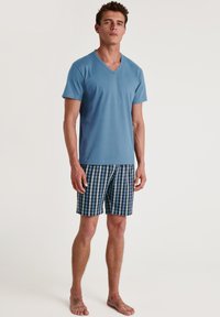 Light blue cotton t-shirt with a V-neck, paired with blue and white checkered shorts. The shorts feature an elastic waistband and side pockets.