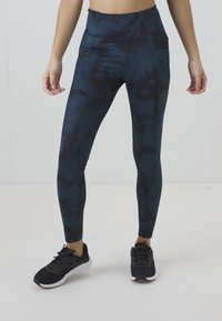Leggings a vita alta e aderenti di colore blu scuro con motivi astratti neri. Realizzati in tessuto elastico, presentano una texture liscia e orlo semplice.