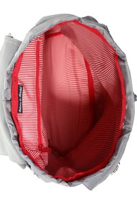 Sac en tissu gris de forme ronde avec un intérieur à rayures rouges. Comprend une poche zippée, des coutures rouges, et une étiquette portant la mention "Bienvenue à Brackel."