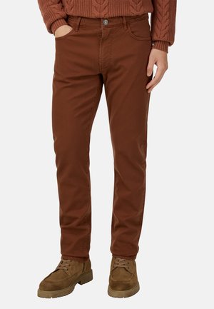 Braune Baumwoll-Chinos mit schmalem Schnitt und Knopfverschluss, ausgestattet mit Vordertaschen und Gürtelschlaufen, kombiniert mit braunen Wildlederschuhen.