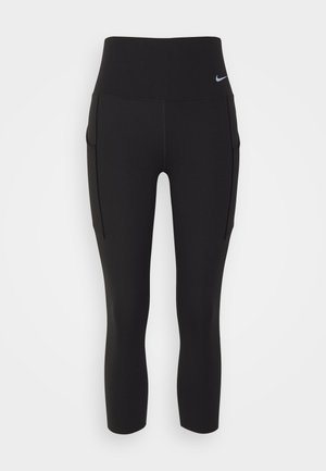 Svarta leggings med hög midja, tillverkade av stretchigt material. Har sidofickor och en liten vit Nike-logga på midjan.