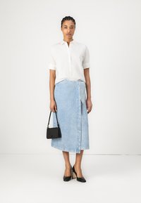 Hvit knapp-up skjorte, lys blå denim omslagsskjørt, svarte høye hæler og en liten svart håndveske. Glatte teksturer og minimalistisk design.