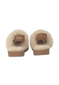 Pantofole foderate in pelliccia beige con un'etichetta in pelle marrone chiaro sulla heel che riporta la scritta "GRUNLAND". Tessuto morbido e suola piatta per il massimo comfort.