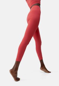 Leggings rossi con una trama liscia e design aderente, caratterizzati da una costruzione senza cuciture e una vita alta. Adatti per l'abbigliamento attivo.