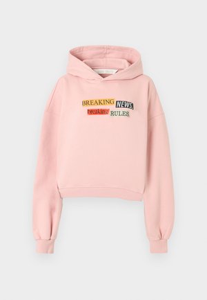 Sweat à capuche court rose en tissu doux avec un design de texte brodé en plusieurs couleurs et polices : "BREAKING NEWS", "breaking" et "RULES."