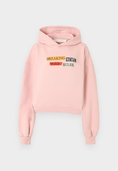 Ροζ κοντή φούτερ με κουκούλα κατασκευασμένη από μαλακό ύφασμα, με κεντημένο σχέδιο κειμένου σε διάφορα χρώματα και γραμματοσειρές: «BREAKING NEWS», «breaking» και «RULES».