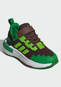 Hnedé a zelené tenisky s textúrovaným zvrškom, s pixelovaným dizajnom, tromi zelenými pruhmi a bielou stredovou podrážkou s textúrovanou špičkou.