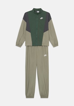 Nike sportovní souprava v zelené a šedé barvě. Bunda má vysoký límec a zip vpředu; kalhoty mají elastické manžety, oboje s logem.