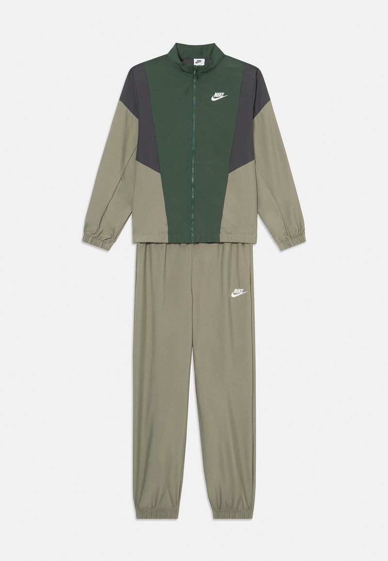 Fato de treino Nike em verde e cinza. A jaqueta tem um colarinho alto e fecho éclair à frente; as calças possuem punhos elásticos, ambas com detalhes do logótipo.