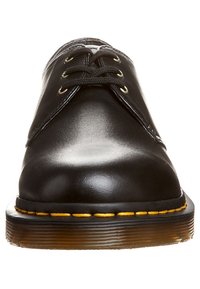 Scarpe di pelle nera con punta rotonda, design classico con lacci, cuciture gialle attorno alla suola e suola in gomma testurizzata.