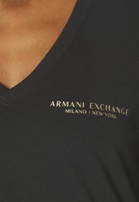 Musta puuvillainen V-pääntie t-paita, jossa on kultainen "ARMANI EXCHANGE MILANO / NEW YORK" -brändäys, sileä pinta ja rento muotoilu.