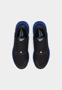 Ζευγάρι μαύρα και μπλε παπούτσια τρεξίματος Reebok, φτιαγμένα από πάνω σε απλό φόντο, με κορδόνια και το λογότυπο της μάρκας στη γλώσσα.