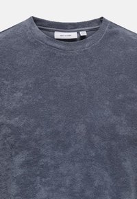 Dunkelgraues Fleece-T-Shirt mit Rundhalsausschnitt, weicher Textur und sanften Farbvariationen. Das Etikett ist am Hals sichtbar.