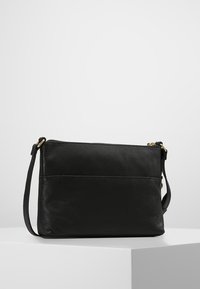 Black leather crossbody bag with a textured finish, featuring a zip closure, adjustable strap, and a back pocket for additional storage.