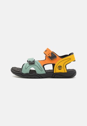 Mehrfarbige Sandalen mit grünen, orangen und gelben synthetischen Riemen, die mit Velcro-Verschlüssen versehen sind, und einer schwarzen strukturierten Sohle.