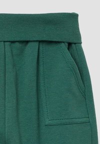 Groene katoenmix broek met een brede elastische tailleband, zijzakken en subtiele plooien voor extra textuur en comfort.