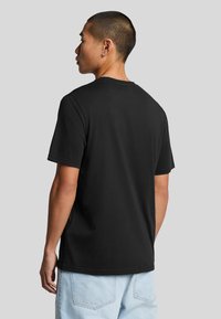 Maglietta nera in cotone con collo rotondo, maniche corte e orlo dritto. Il tessuto appare liscio, senza ulteriori motivi o dettagli.