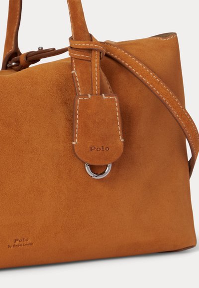 Τσάντα Polo από σουέτ σε καφέ ταμπά της Ralph Lauren με ραμμένη δερμάτινη ετικέτα αποσκευών και ρυθμιζόμενο λουρί ώμου, με κοντινή εικόνα λεπτομερειών.