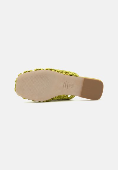 Vue de la semelle d'une sandale jaune tissée à enfiler avec un talon carré et une semelle extérieure beige texturée antidérapante, marques de la marque et de la taille visibles.