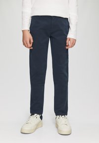 Marineblauwe katoenen broek met een slim fit, subtiele textuur en zijzakken. Gecombineerd met witte sneakers met een textuurontwerp.