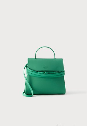 Piccola borsa verde Moschino con manico superiore e tracolla regolabile, esposta su sfondo bianco semplice.