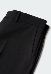 Pantalon noir plié avec passants pour ceinture et poche latérale, présenté sur fond blanc.