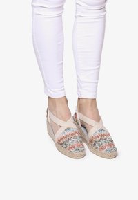Espadrilles de cuña con parte superior de textil trenzado multicolor que presenta un patrón de zigzag, correas elásticas cruzadas y suelas de yute natural.