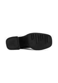 Semelle de chaussure noire avec une texture en caoutchouc antidérapant, comportant des rainures horizontales et une forme rectangulaire, finie avec des bords lisses et des accents cousus.