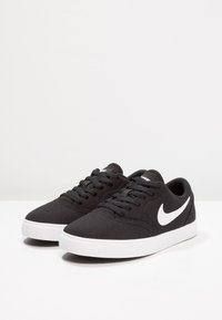 Mustad mustad ketsid valge kummist tallaga ja valge Nike swoosh logoga. Omavad lamepaelu ja pehmendatud kaela mugavuse jaoks.