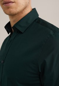 Donkergroene button-up shirt met een gestructureerde kraag, gemaakt van een gladde stof, met knoopsluiting aan de voorkant en nette stiksel-details.