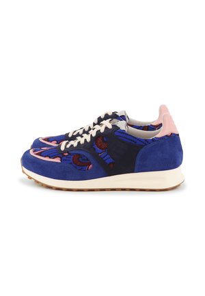 Paire de baskets bleues avec tissu à motifs multicolores, lacets blancs, accents roses au talon et semelle en caoutchouc blanc cassé sur un fond blanc.