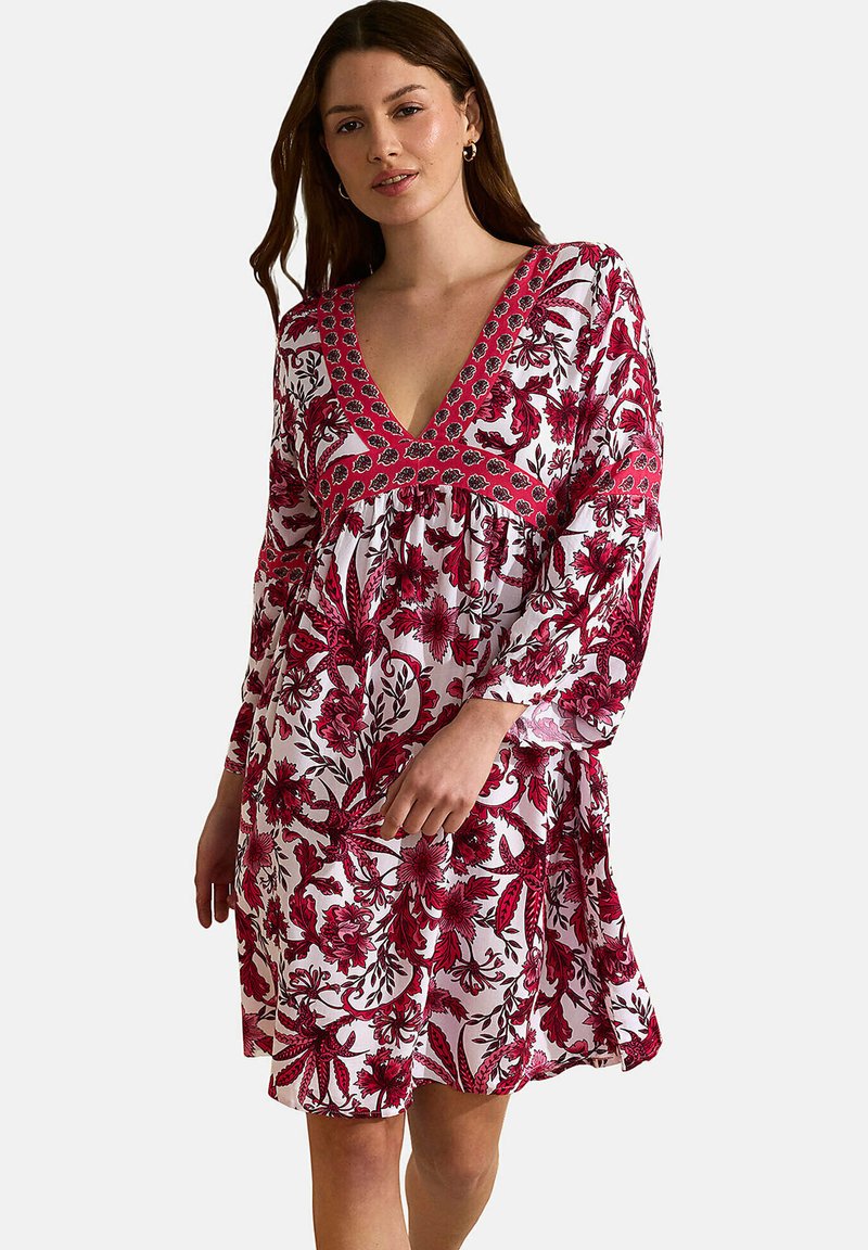 Robe blanche avec motif floral rouge, décolleté en V profond et manches longues. Dotée d'un encolure brodée et d'une silhouette fluide. Tissu léger.