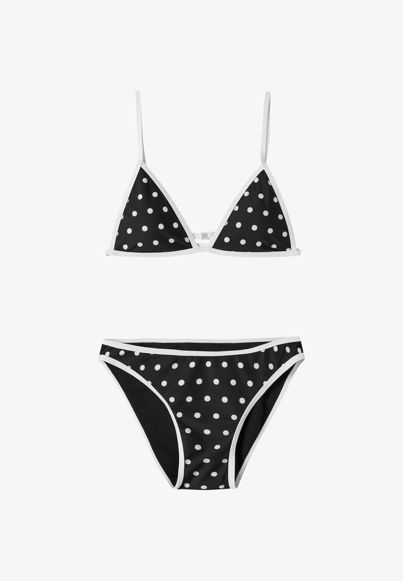 Bikini noir à pois blancs, composé d'un haut triangle avec des bretelles fines et d'un bas taille basse assorti bordé de blanc.