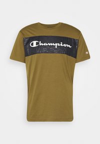 Olivově zelené tričko s krátkými rukávy, černý horizontální pruh a velké bílé logo "Champion" na hrudi, malé logo na levém rukávu.