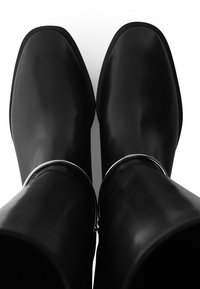 Zwarte rubberen regenlaarzen met een gladde afwerking, vierkante tenen en een zilveren accent aan de bovenkant. Ontworpen voor duurzaamheid en waterbestendigheid.